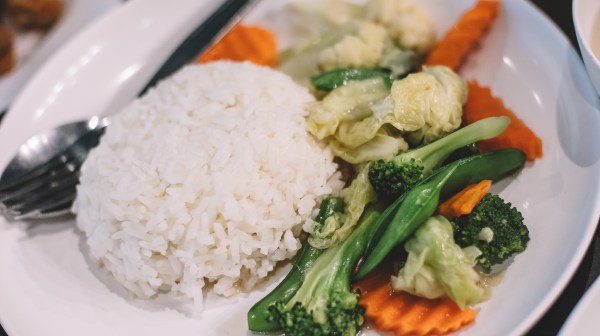 Plate of white rice with broccoli, carrots, and other vegetables.